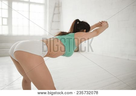 Young Sporty Woman Doing Streching Exercises In Bright Interior. Correct Posture. Perfect Rear. Prot