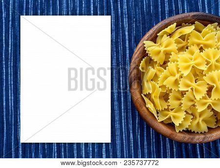 Farfalle Raw Pasta In A Wooden Bowl On A Striped White Blue Cloth Background With A Side. Close-up W