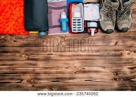 Top View Of Equipment For Hiking And Wooden Background With Copy Space. Items Include Trekking Shoes