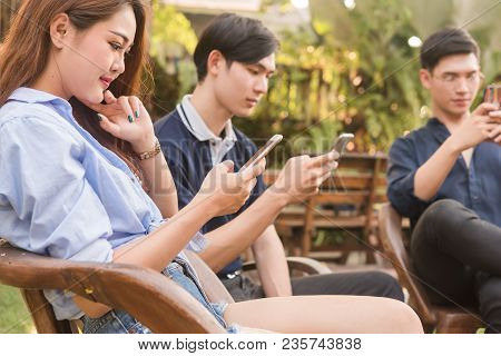 Group Of Six Teenagers Play Social Media On Smartphone In Afternoon