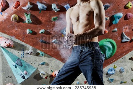 Man Climber Preparing To Climb Indoors In Bouldering Gym With Dramatic Light. Man Using Chalk. Hands