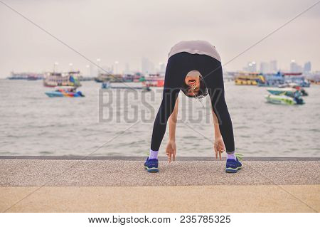 Sports Concept. Beautiful Girl Is Exercising On The Beach With Warm Up. Beautiful Girl Is Happy To E
