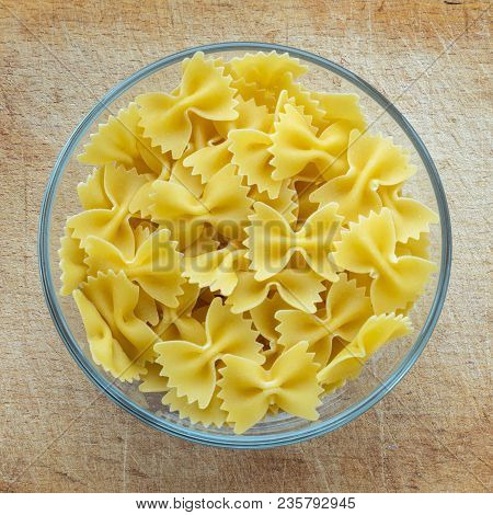 Farfalle Raw Farfallini Pasta In A Glass Bowl On A Wooden Cutting Board, Texture Background, In The 