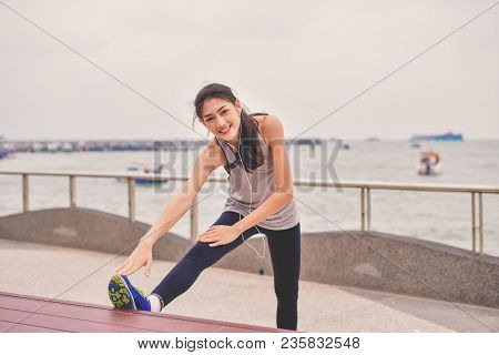 Sports Concept. Beautiful Girl Is Exercising On The Beach With Warm Up. Beautiful Girl Is Happy To E