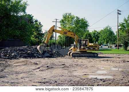 Joliet, Illinois / United States - July 27, 2017: A Cat 320 Hydraulic Excavator Digs Up A Parking Lo