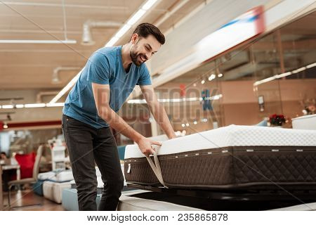 Young Bearded Man Is Testing Mattress In Furniture Store. Orthopedic Mattress For A Healthy Posture.