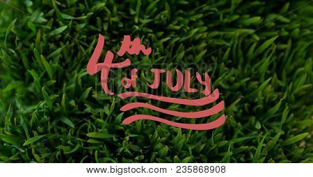 Red fourth of July graphic against grass