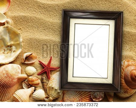 Pictue frame on shells and sand background. Copy space.