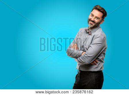 Middle age man, with beard and bow tie with crossed arms confident and happy with a big natural smile laughing