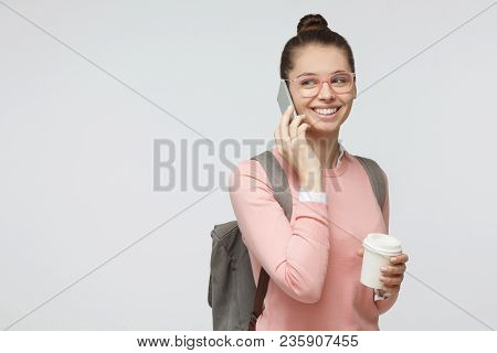 Studio Photo Of Student Girl Isolated On Grey Background With Backpack On Her Back, Holding Takeaway