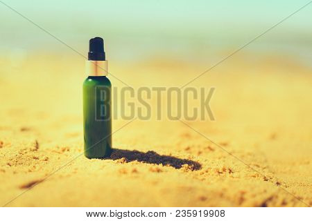 Bottle Of Sunscreen In Sand Against Sea Background With Copyspace. Vacation And Travel Wallpaper. Sk