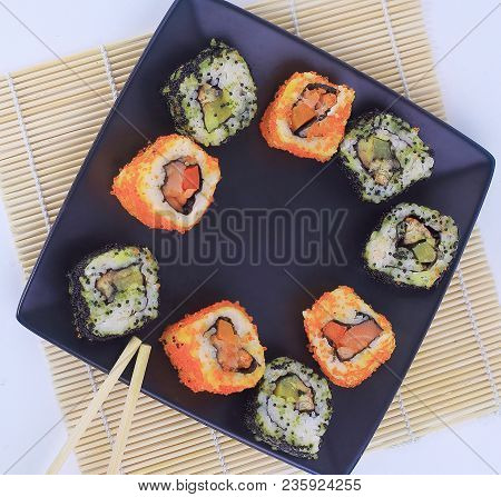 Different Types Of Maki Sushi On A Black Plate.isolated On White Background