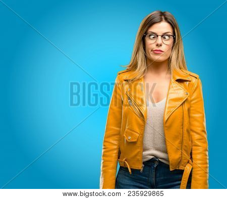 Beautiful young woman making funny face fooling, blue background