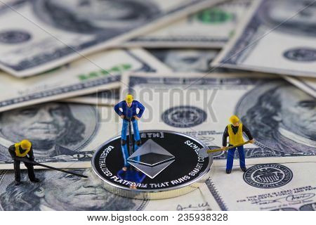 Miniature People Worker Digging Silver Ethereum Coin On Hundred Dollar Bill. Virtual Cryptocurrency 