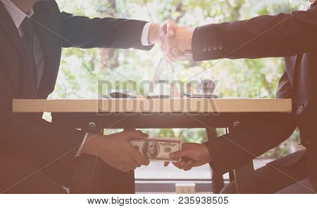 Corruption Concept. Close Up Of Two Businessman Shaking Hands And Receiving Dollars Money. Bribe Mon