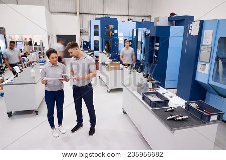 Engineers Meeting On Factory Floor Of Busy Engineering Workshop