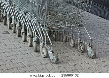 A Row Of Gray Shopping Carts From A Supermarket Stand On The Street On The Sidewalk
