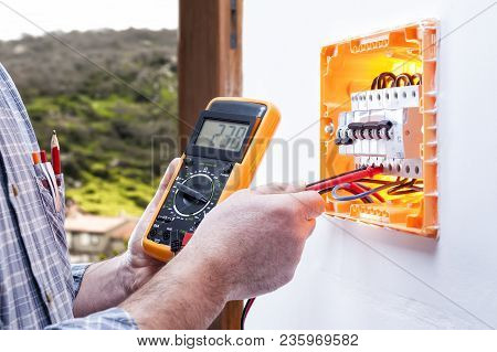 Electrician Technician At Work On A Residential Electrical Panel, Measures The Voltage With The Test