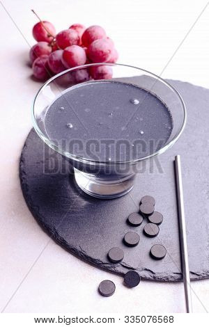 Black Yogurt With Activated Carbon And Grapes On A White Background.