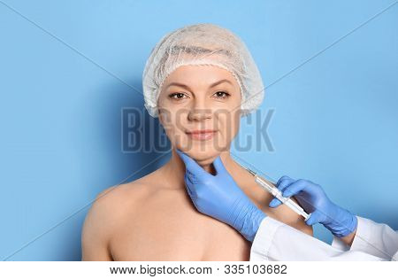 Mature Woman With Double Chin Receiving Injection On Blue Background