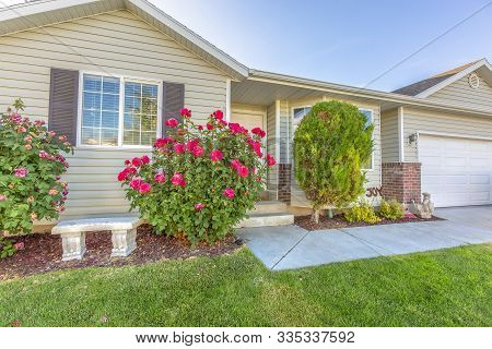 Facade Of A One Storey Single Family Home With Plants And Flowers In The Yard