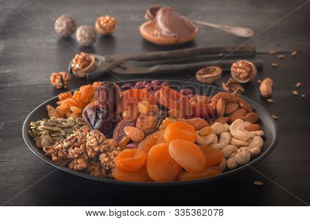 Mix Of Dried Fruits, Chocolate Paste And Nuts On A Black Table. Low Key. Close-up.