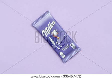 Milka Chocolate Tablet In Classic Violet Wrapping On Lilac Background. Milka Is Brand Of Chocolate C