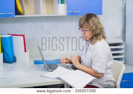 Happy Senior Doctor With Clipboard At Hospital Reception