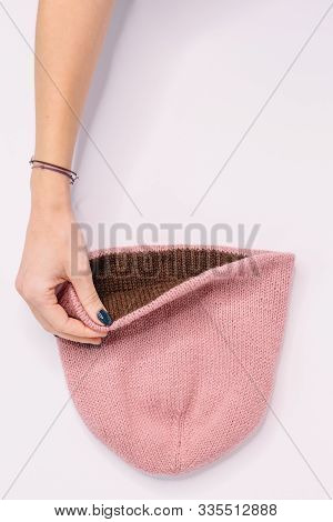 Hand Of Caucasian Woman Hold Bilateral Pink-brown Knitted Beanie Hat. Warm Winter Wool Self-made Clo