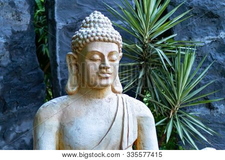 Beautiful Buddha Statue Shot From Side With Blue Rocks In The Background. Religion Concept