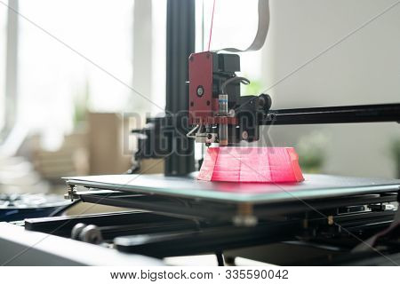 Printhead of 3d printer moving over foundation of pink round object on working layer during process of printing