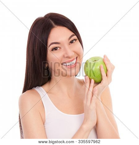 Cute woman with beautiful snow-white smile holding green apple. Healthy lifestyle and nutrition, dieting, weight loss, cosmetology, dental care and healthy teeth con?ept. Close up portrait