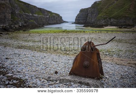 A Rusty, Abandoned Piece Of Machiney That Has Gears, Rests On A Rocky Beach At Geodha Smoo At Smoo C