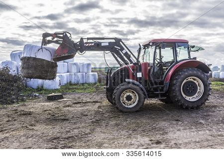 Wheel Tractor With A Lift For Carrying Bales With A Silo. Daily Work At A Dairy Farm. Podlasie, Pola