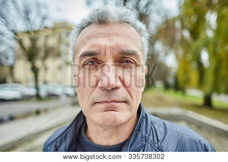 Aged Serious Man Is Standing Outdoors. Portrait Of Mature Sad Businessman About 56 Years Old On The 