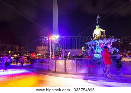 Berlin, Germany - Decemeber 18, 2018: People Enjoy Ice Skating Around The Neptune Fountain At The Ch