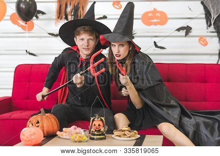 Wicked Caucasian Couple Dressed Up As Wizard And Witch. In Their Hands Holding A Trident, Which Made