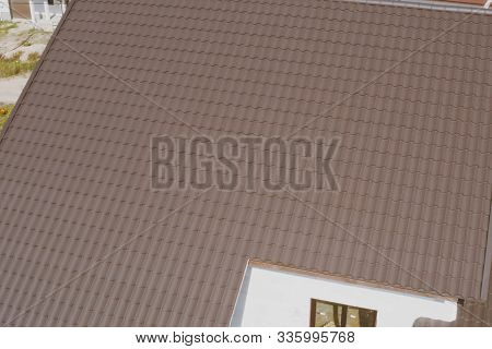 Modern Roof Made Of Metal. Brown Metal Tile On The Roof Of The House. Corrugated Metal Roof And Meta