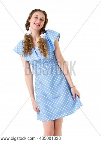 Pretty Teenage Girl Holding Hem Of Her Dress. Studio Shot Of Beautiful Smiling Blonde Girl With Two 