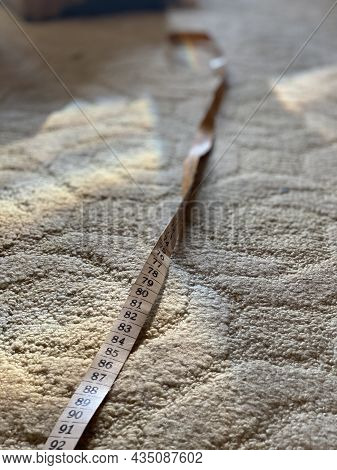 A Rainbow And Tape Measure On An Old Patterned Textile Floor.