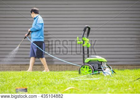 Washer Power Machine For Cleansing House On Yard With Blurred Background Of Man In Blue Cloth Clean 