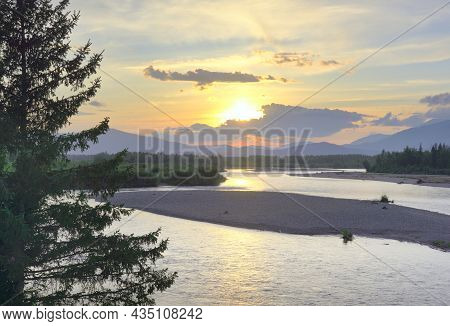 The River Bank In The Altai Mountains Under The Golden Evening Sky. Siberia, Russia