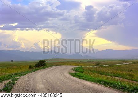 Thick Cumulus Clouds In The Evening Over A Mountain Plain With A Rural Road. Siberia, Russia
