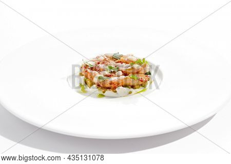 Restaurant dish - shrimp tartare with avocado, cream cheese, sweet chilli sauce on white plate. Ceviche with marinated prawn, avocado and spicy vegetables. Prawn tartare isolated on white background