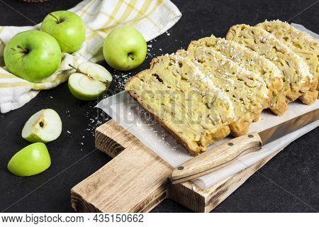 Sliced Apple And Coconut Oaf Cake On Wooden Cutting Board On Dark Background