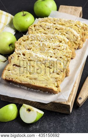 Sliced Apple And Coconut Oaf Cake On Wooden Cutting Board On Dark Background