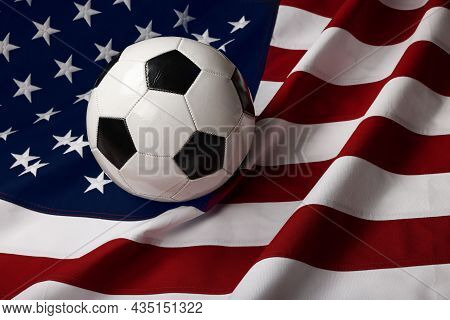 Close Up Worn Black And White Soccer Football Ball Over American Flag Background, High Angle View