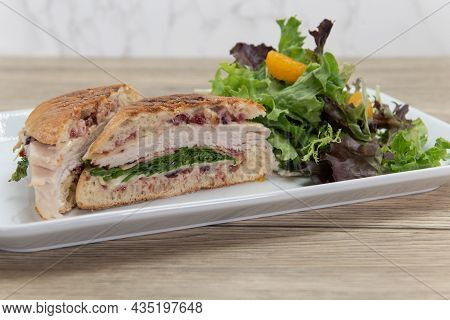 Turkey Panini Sandwich Showing Layers Of Provalone, Bacon, Mozzarella, And Arugula Served With A Sal
