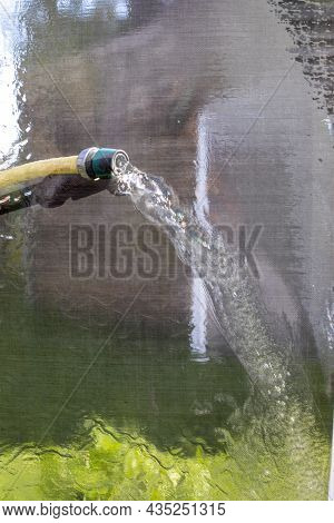 Wash Mosquito Nets From A Hose With Water Close-up Outside Vertical
