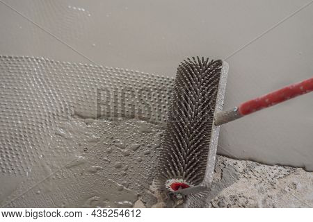 Plasterer During Floor Covering Works With Self-levelling Cement Mortar, Uses A Needle Roller